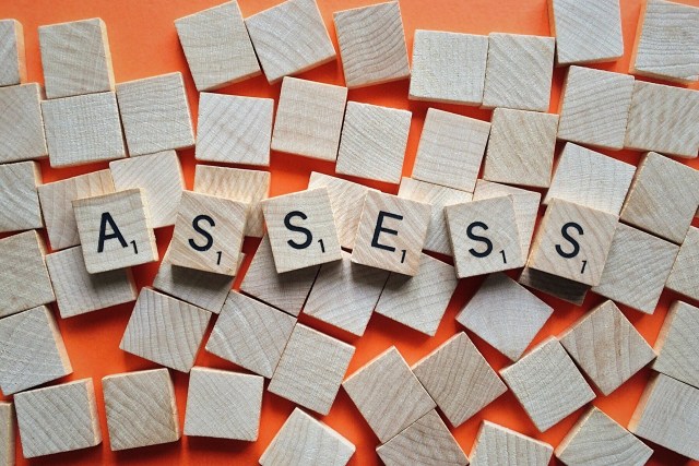 Wooden alphabet tiles spelling 'Assess'